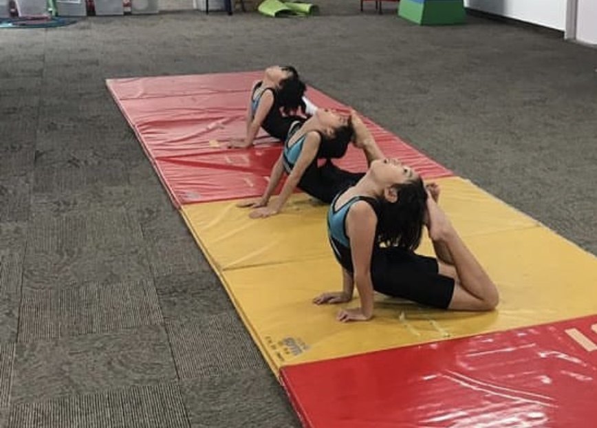 Gymnasts practising flexibility on mats